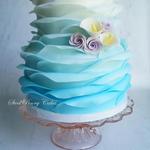 Fondant ruffle wrap in blue ombre with sugar roses and calla lilies.